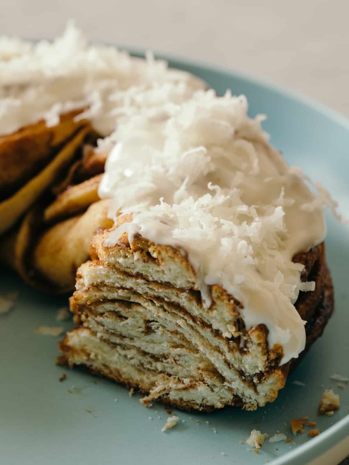 A close up of sliced brown butter braided cinnamon roll cake topped with shredded coconut.