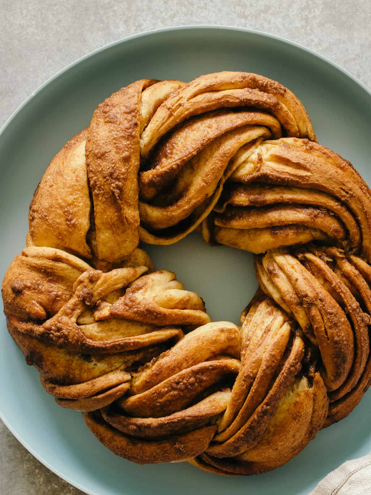 Naked brown butter braided cinnamon roll cake on a plate.
