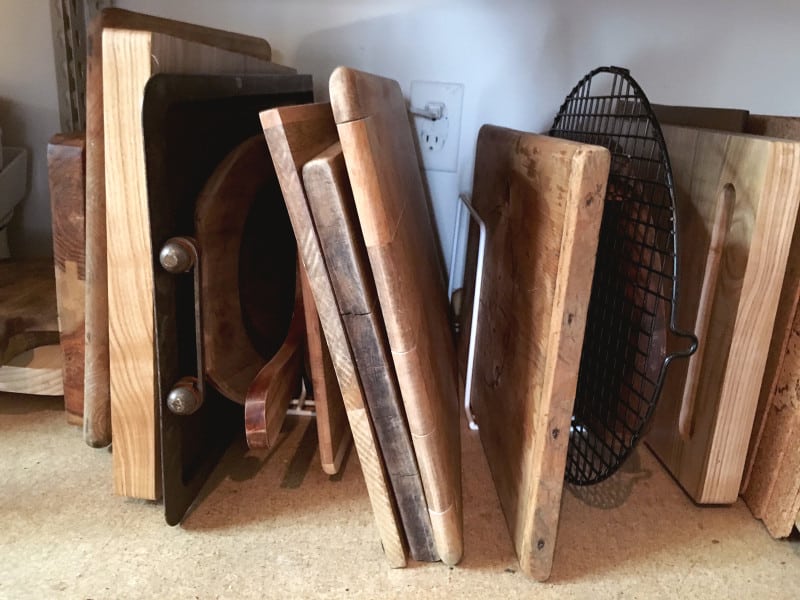 A close up of a variety of wooden cutting boards standing up in racks.