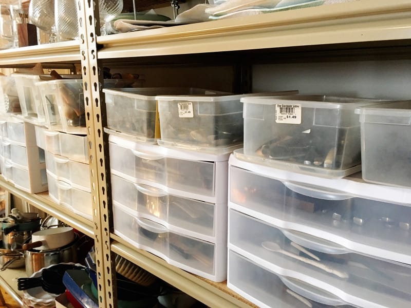 A close up of organized bins of flatware on shelves.