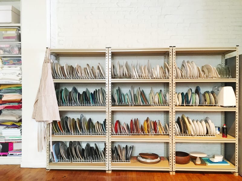 Shelves full of a variety of different colored and sized plates in plate racks.