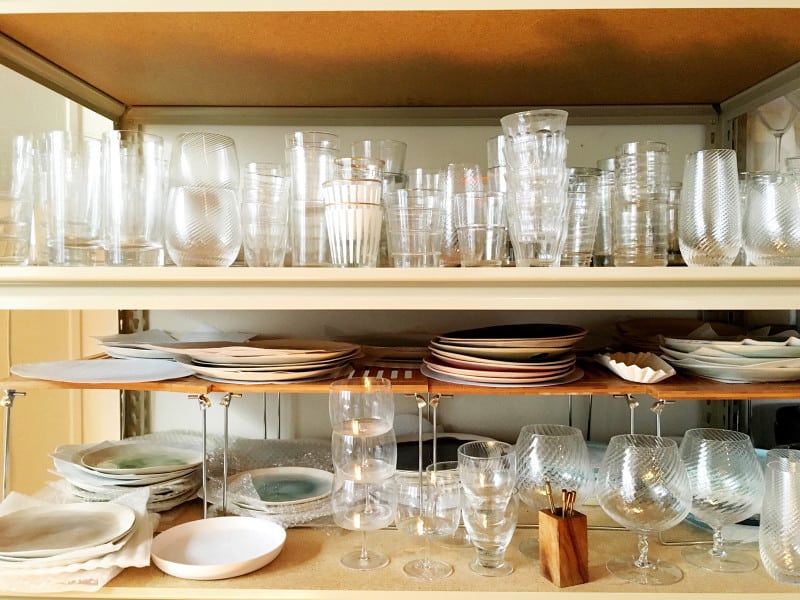 A close up of shelves with stacked glasses and plates.