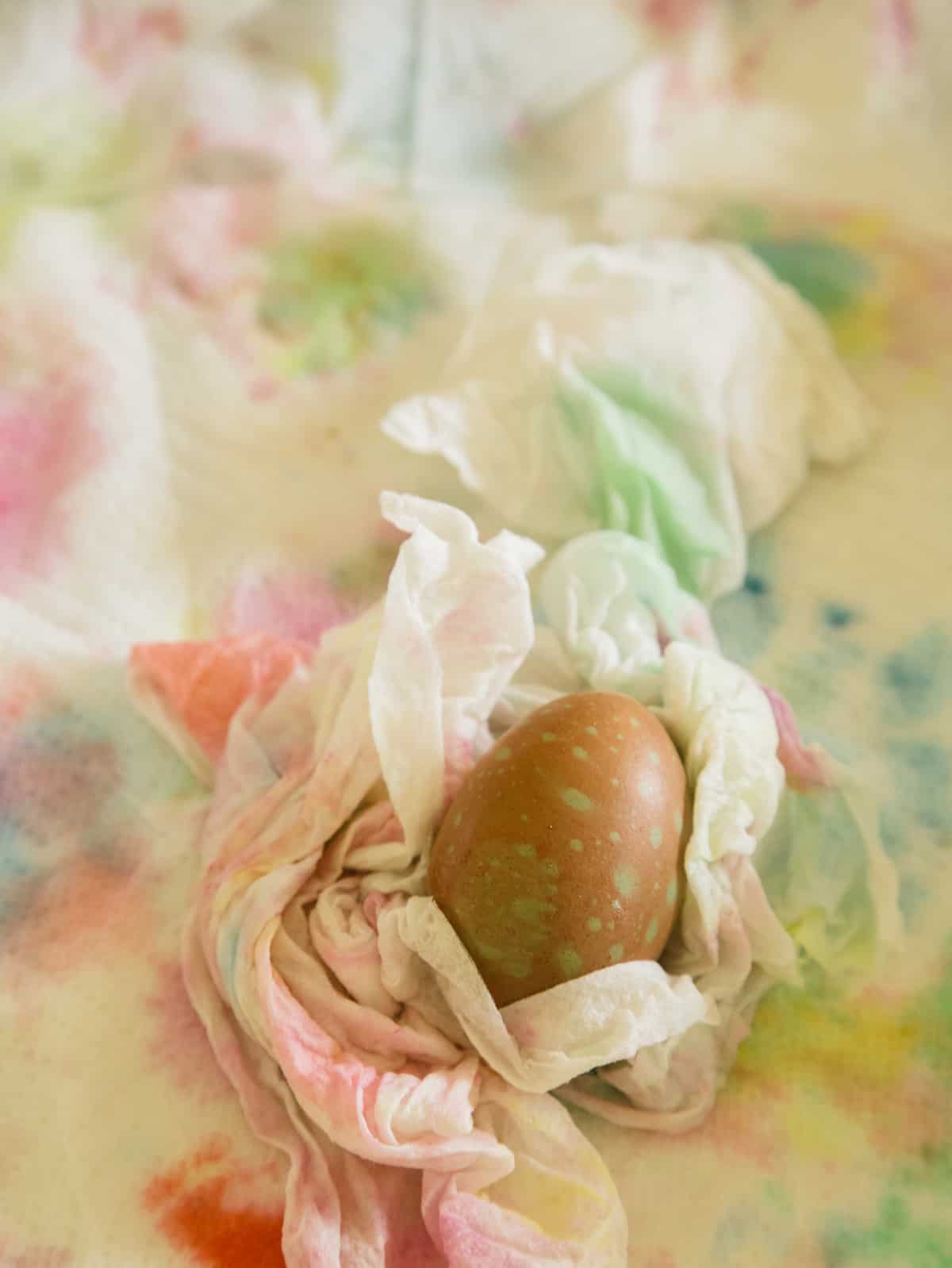 A close up of a finished spotted dyed egg resting in a paper towel.