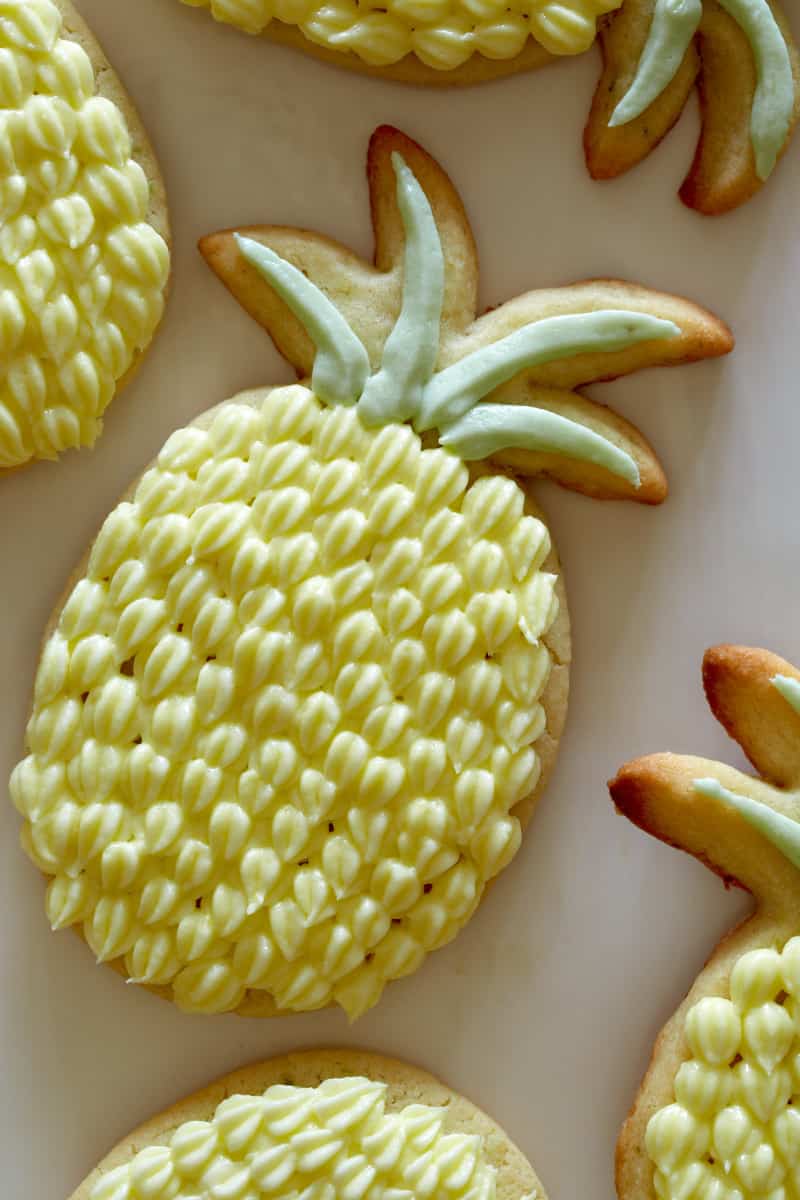 A close up of pineapple shaped lime sugar cookies with pineapple buttercream.