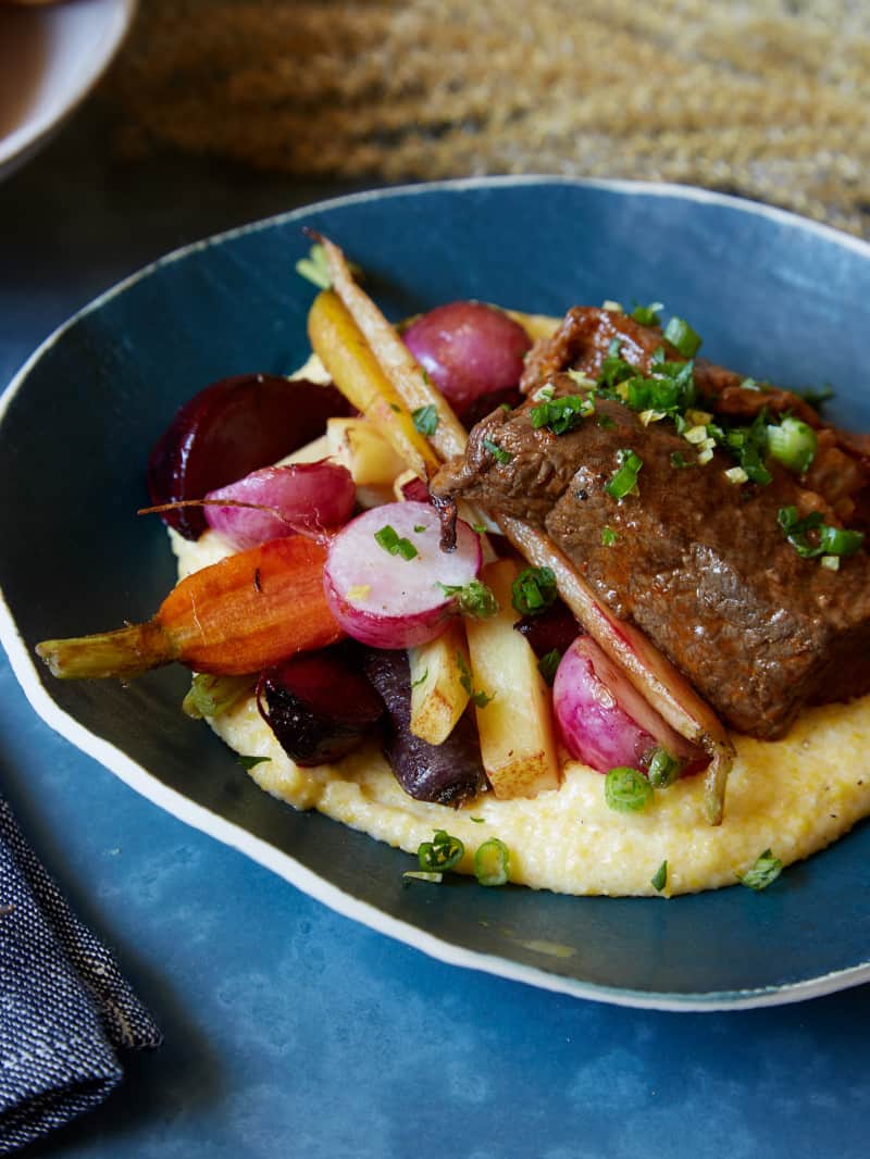 A bowl of white wine braised short ribs with vegetables over white cheddar polenta.