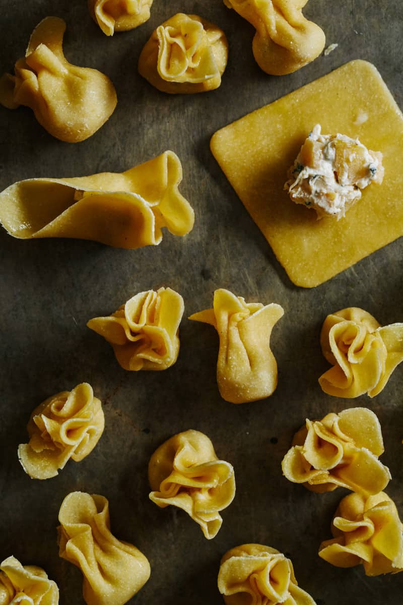 Process shot of caramelized apple and herb fiocchi being folded into shape.