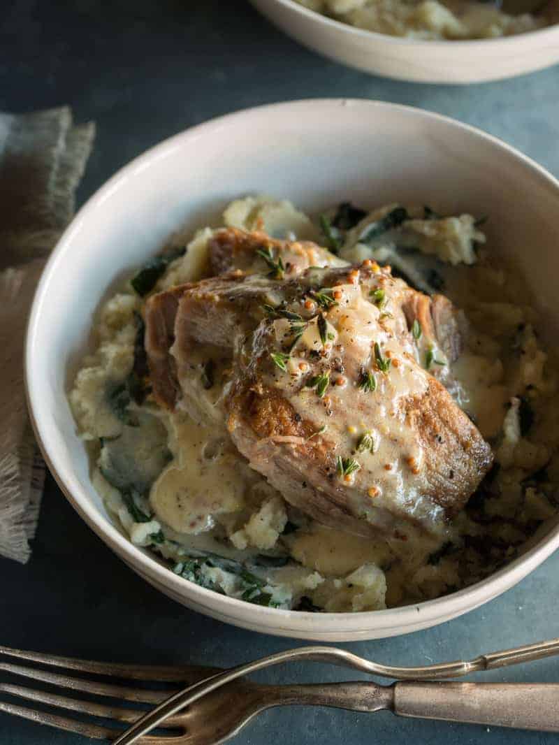 Milk braised pork shoulder over browned butter colcannon in a bowl.