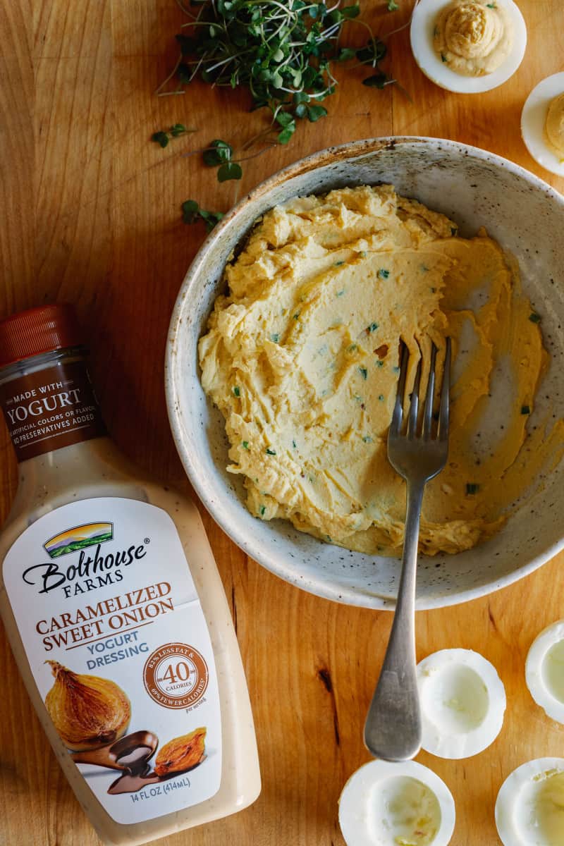 Onion herb deviled egg filling with a fork and a bottle of Bolthouse Farms yogurt dressing.