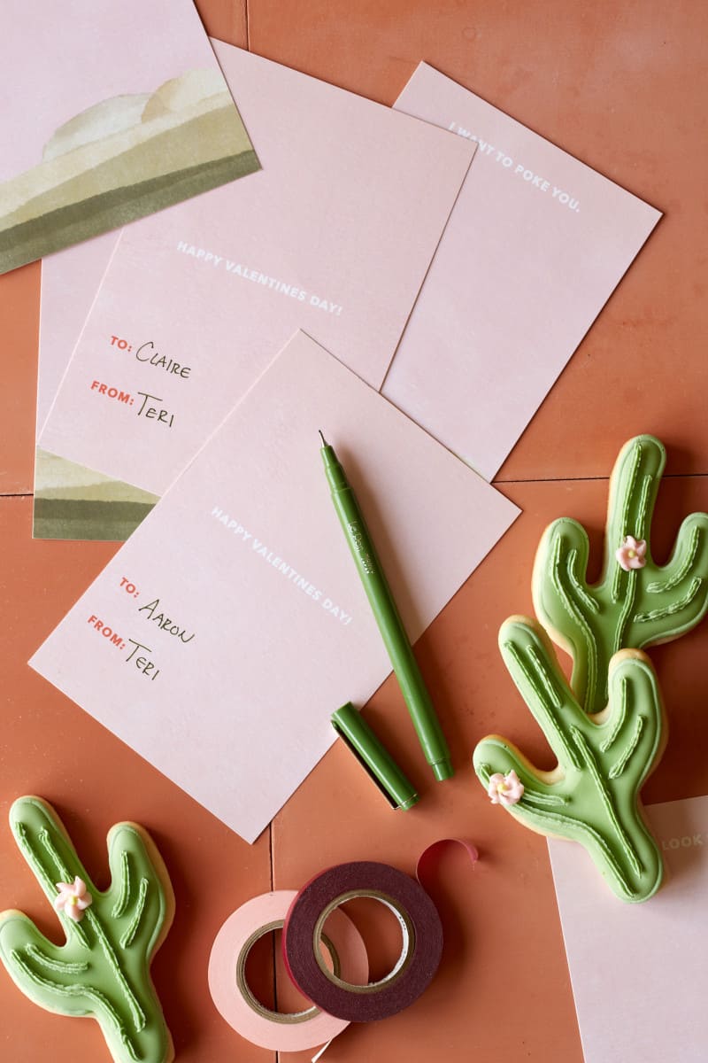 DIY valentines cards and a pen next to cactus cookies.
