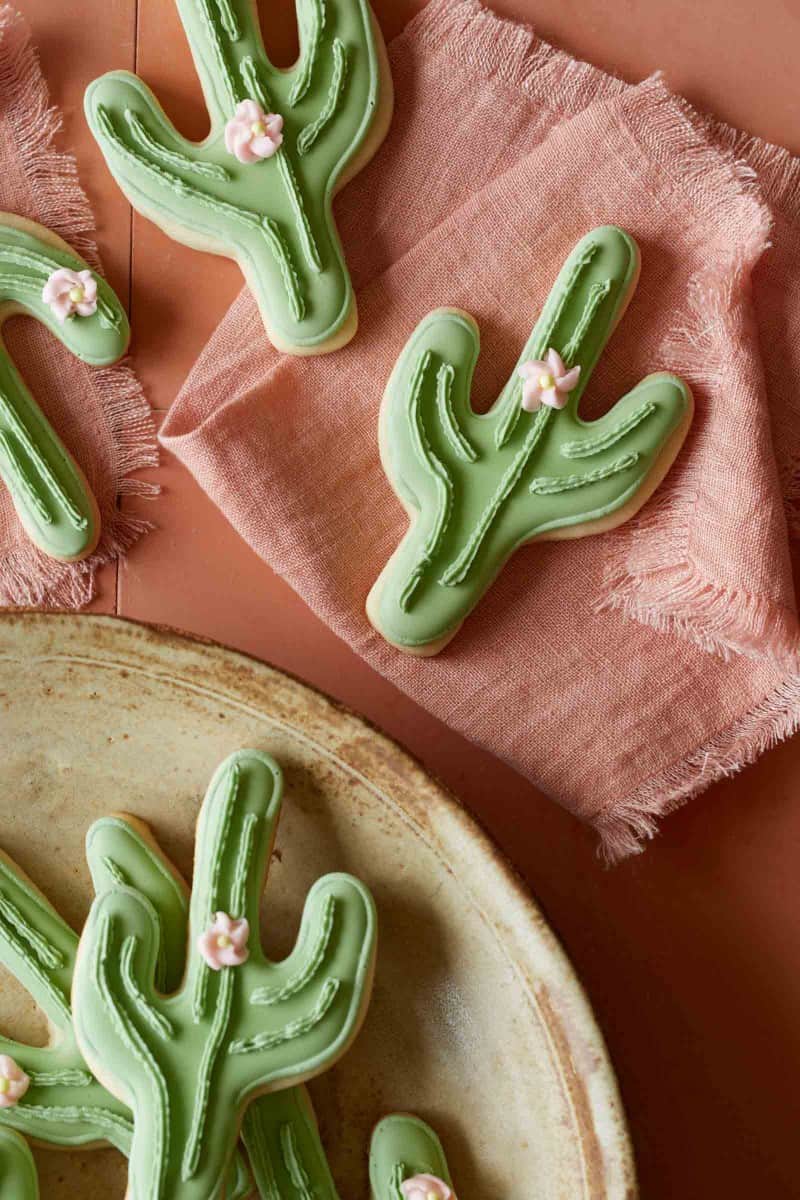 Cactus cookies on a plate and pink linens.