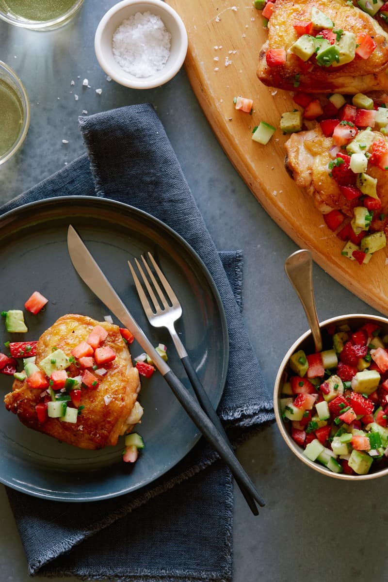 A plate with a roasted chicken thigh and strawberry avocado salsa on top and on the side.