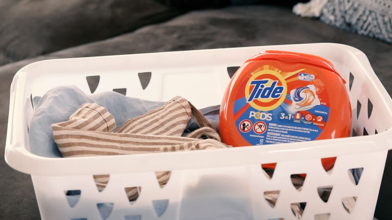 Tide pods in a laundry basket with linens.