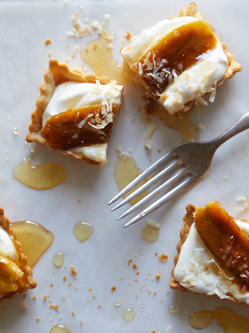Banana, coconut, and honey cream tarts  cut in half with a fork.