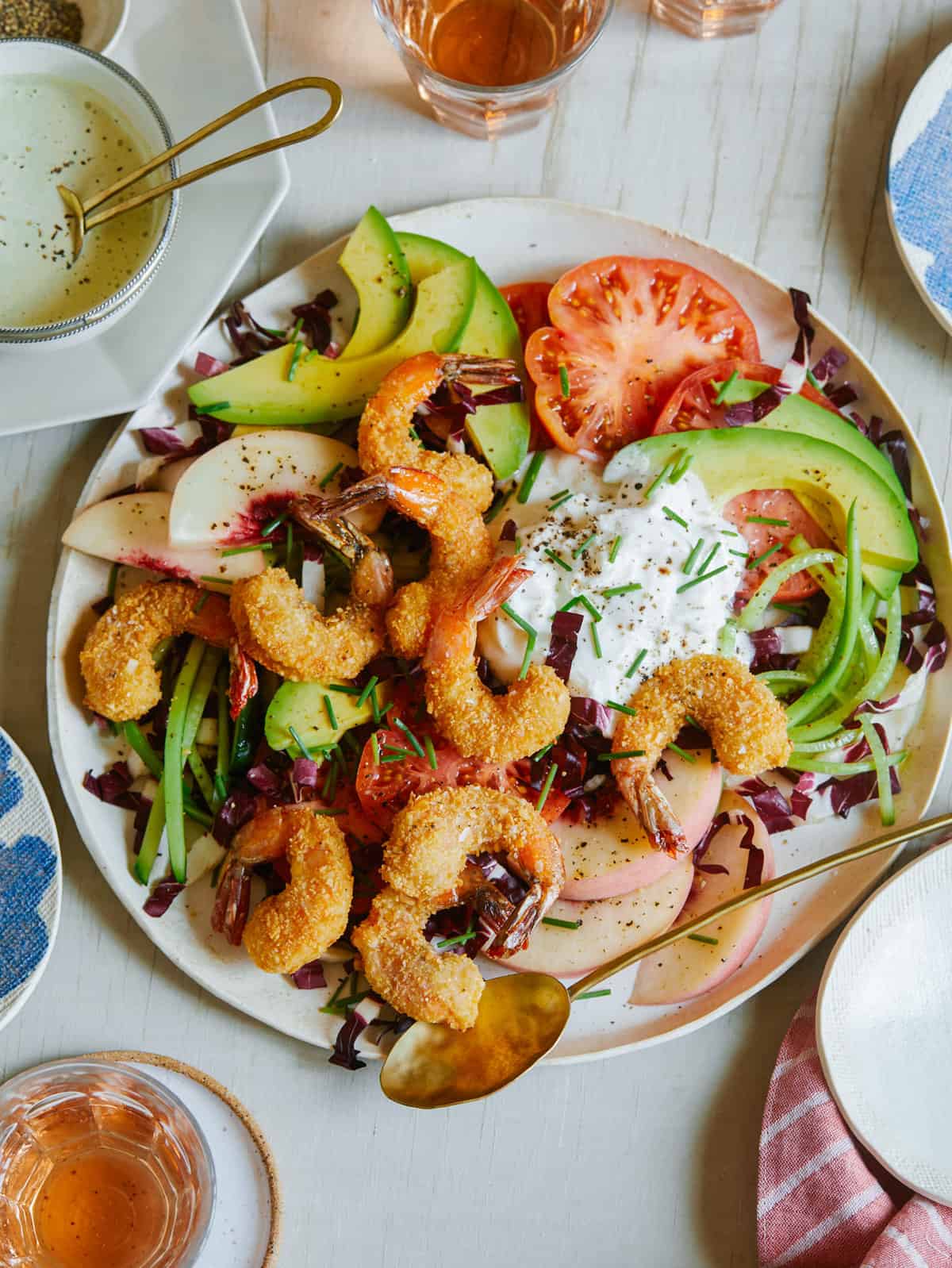 Fried coconut shrimp on top of a bed of lettuce and seasonal summer ingredients.