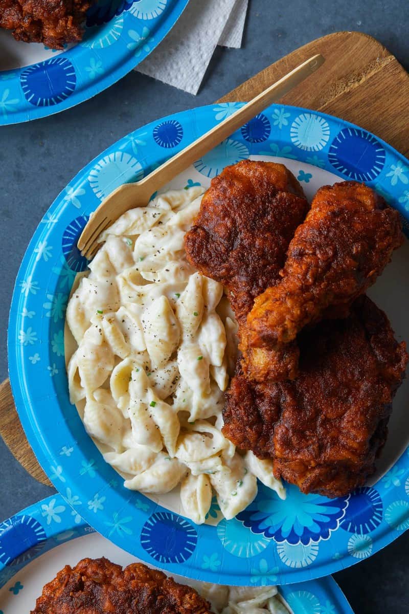 A close up of a Dixie paper plates of Nashville hot chicken with mac and cheese.