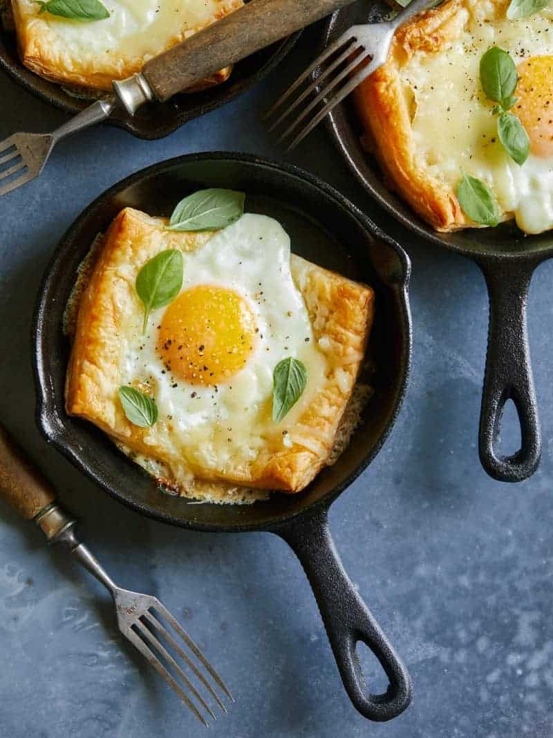 Simple egg and cheese tartlets in individual skillets with forks.