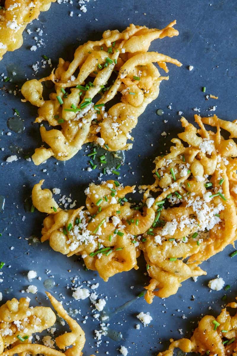 A close up of a savory funnel cake with bite pulled off. 