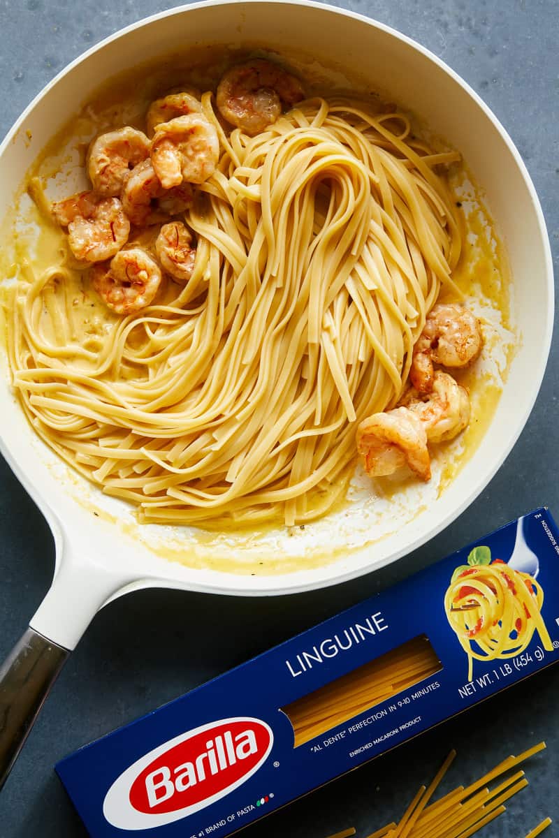 Shrimp linguine with cream sauce in a skillet next to a box of Barilla linguine.