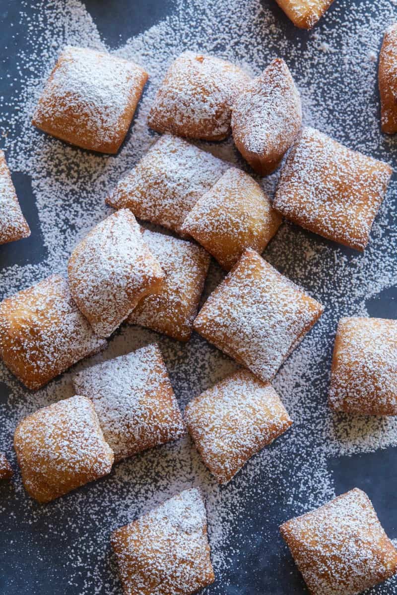 A close up of chai spiced buttermilk beignets covered in powdered sugar.