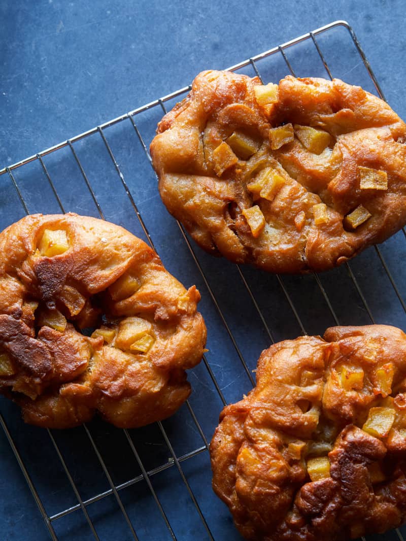 A close up of apple fritters on a cooling rack.