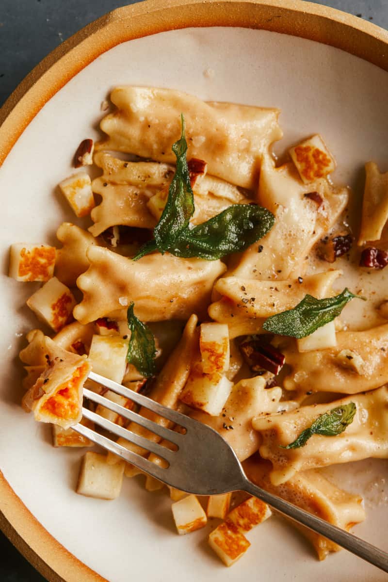 A close up of creamy sweet potato agnolotti on a plate with a fork.