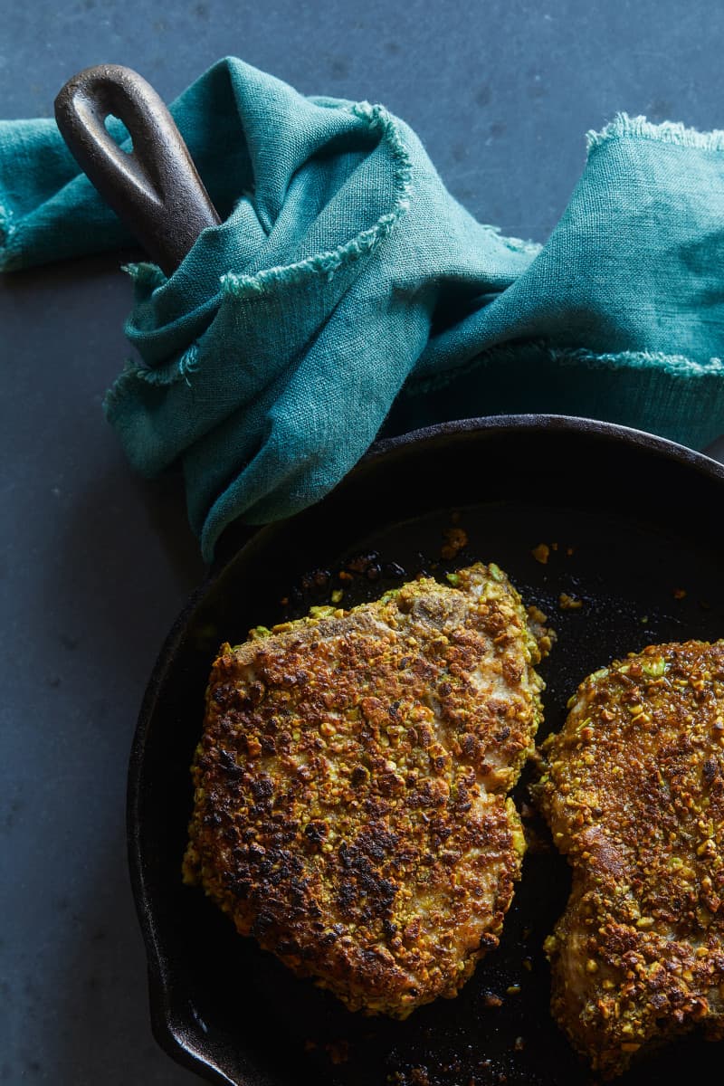 Pistachio crusted pork chop in a skillet.