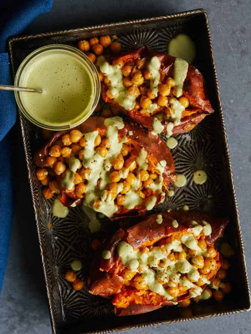 A plate of chickpea stuffed sweet potatoes with cilantro garlic cashew sauce.