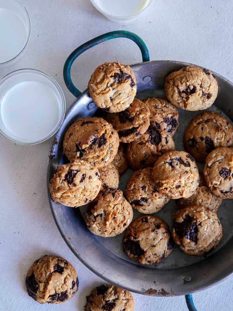 A plate of chai, chocolate chip, coconut, cookies and milk.