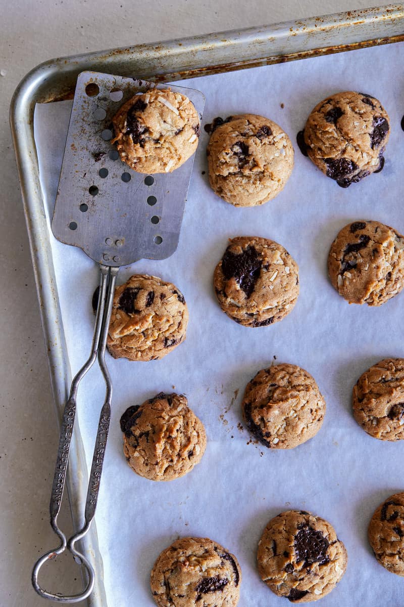 Baked chai, chocolate chip, and coconut cookies on a baking sheet with a spatula.