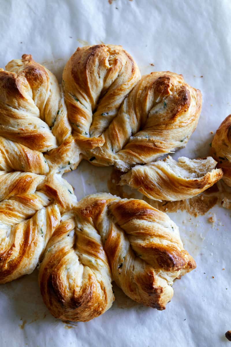 A close up of herb and cheese braided star bread with some pulled off.