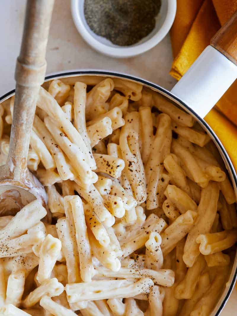 Vegan stovetop mac and cheese in a pot with a wooden spoon.