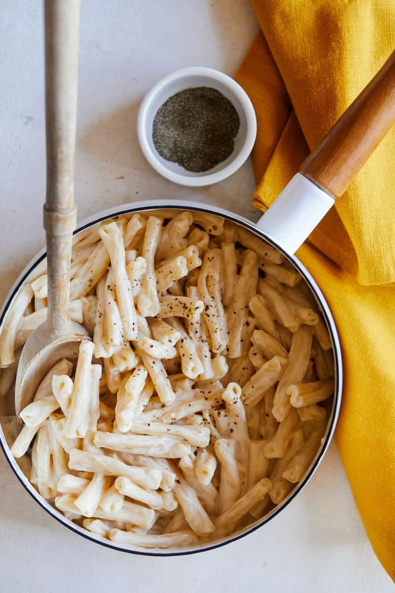 A pot of vegan stovetop mac and cheese with a wooden spoon.