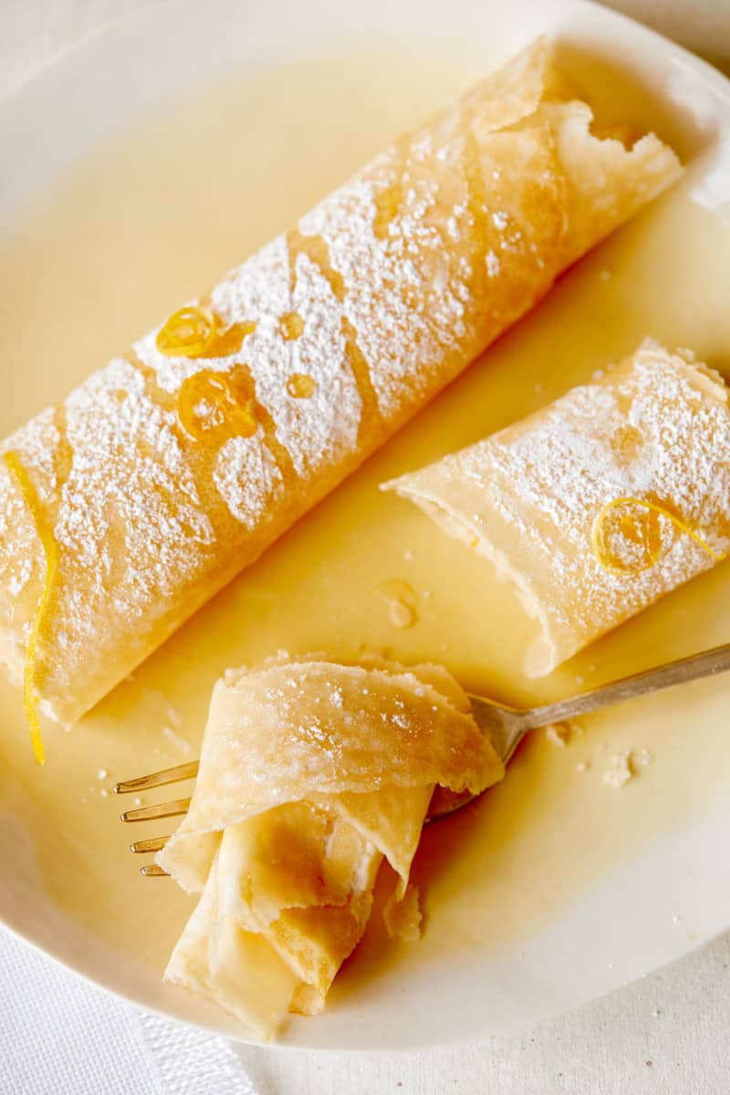 Meyer lemon and ricotta stuffed crepe with a bite cut off with a fork..