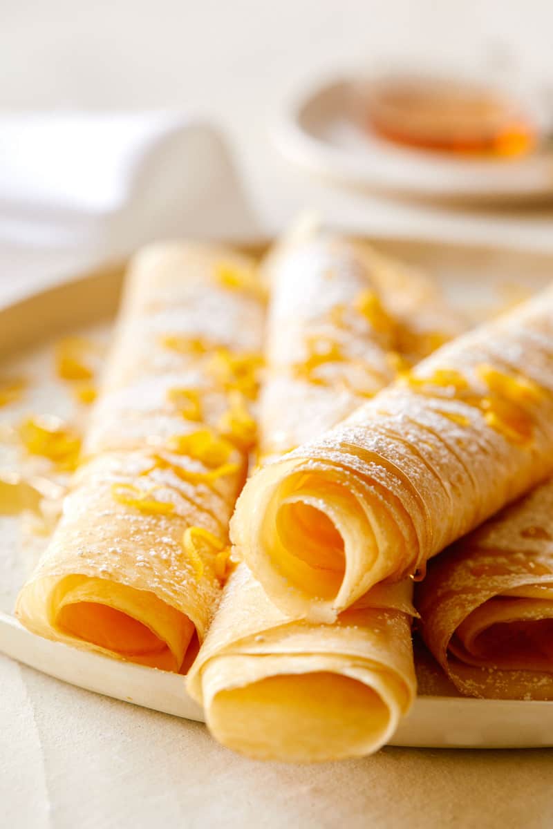 A close up of meyer lemon and ricotta stuffed crepes on a plate.