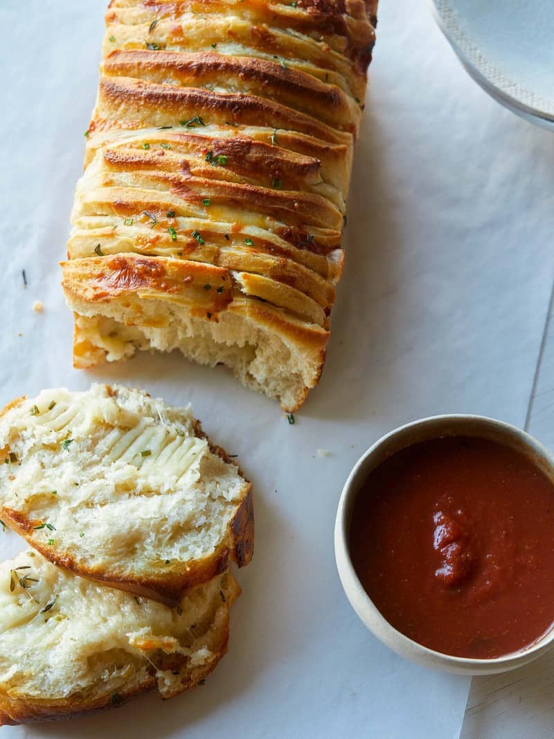 A close up of cheesy pull apart bread with sauce on the side.
