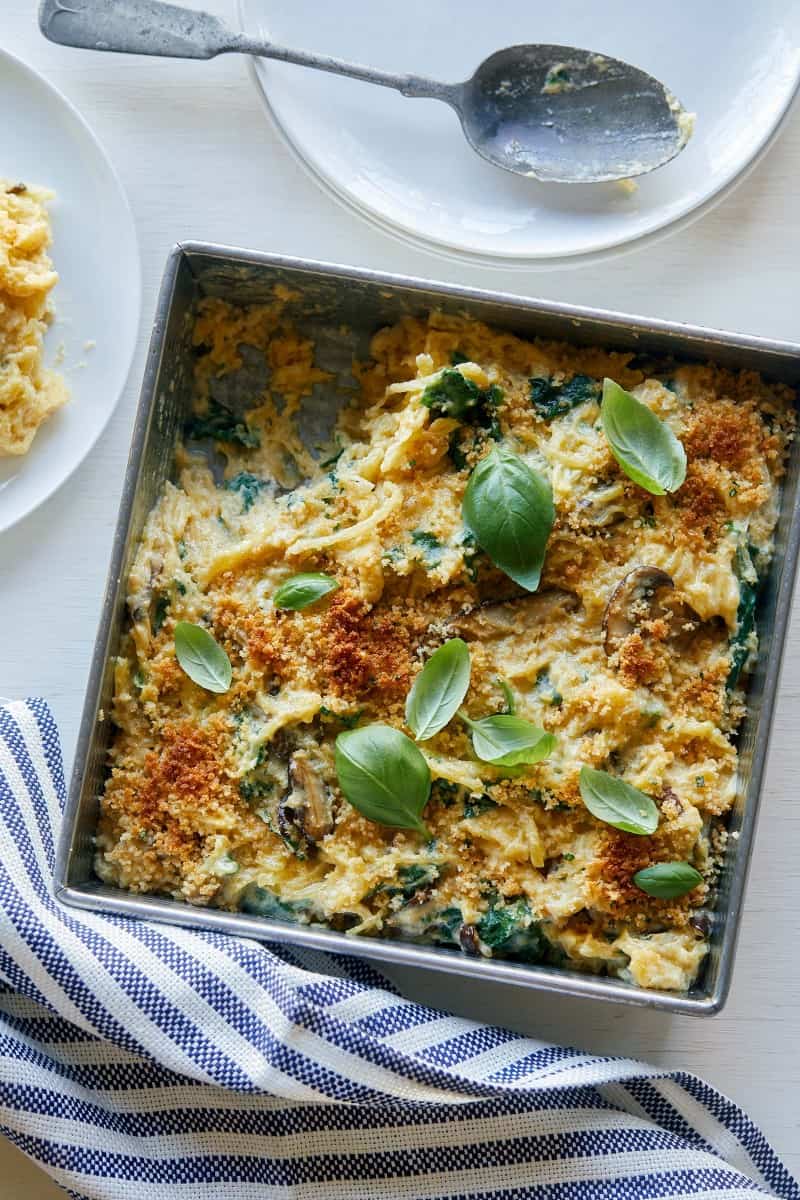 A pan of creamy vegan spaghetti squash, wild mushroom, and spinach bake.