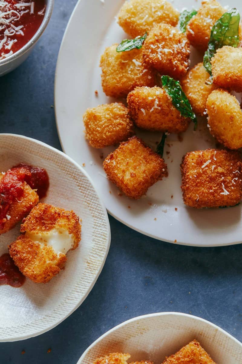 A close up of a platter and a small plate of hallumi nuggets with marinara sauce.