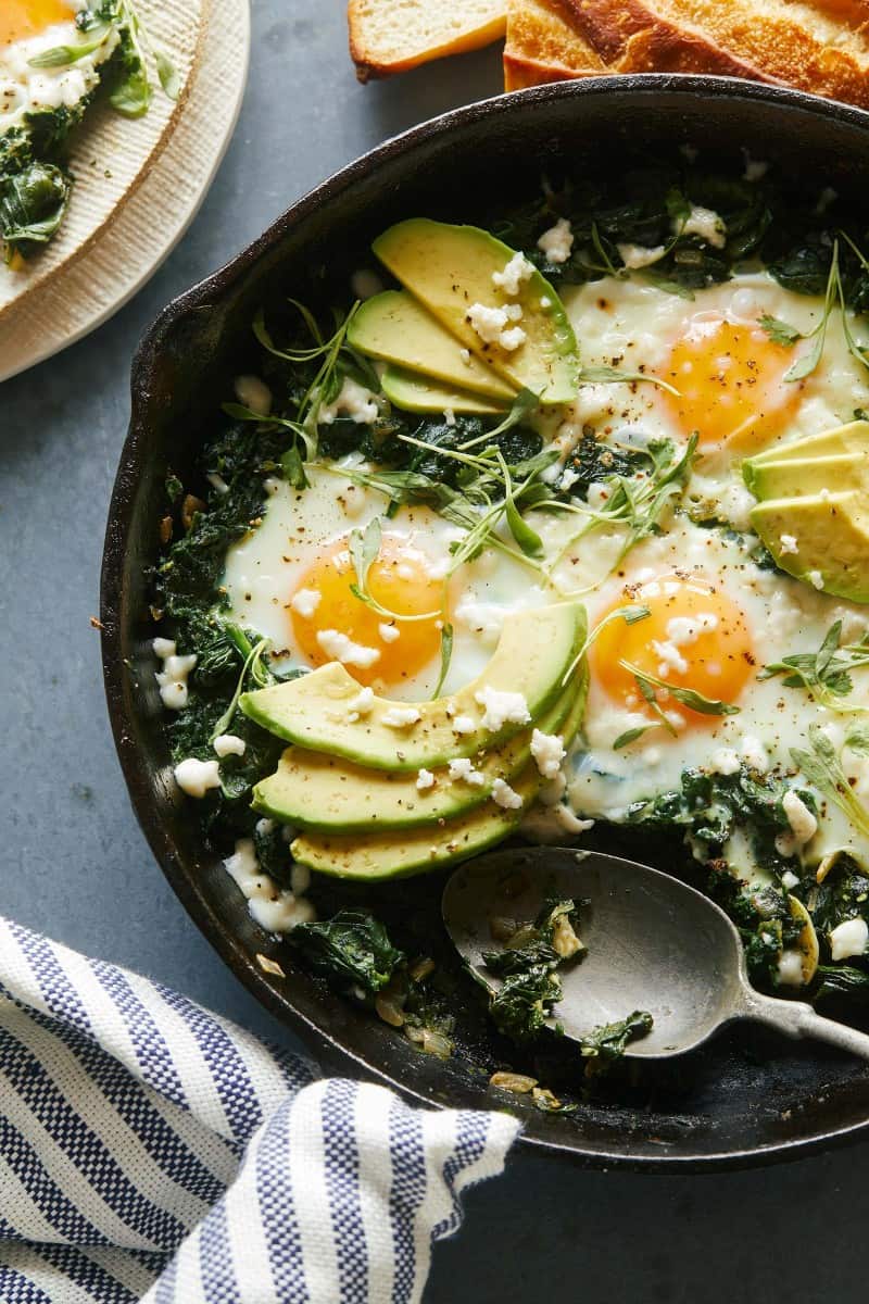A skillet of green shakshuka with a spoon.