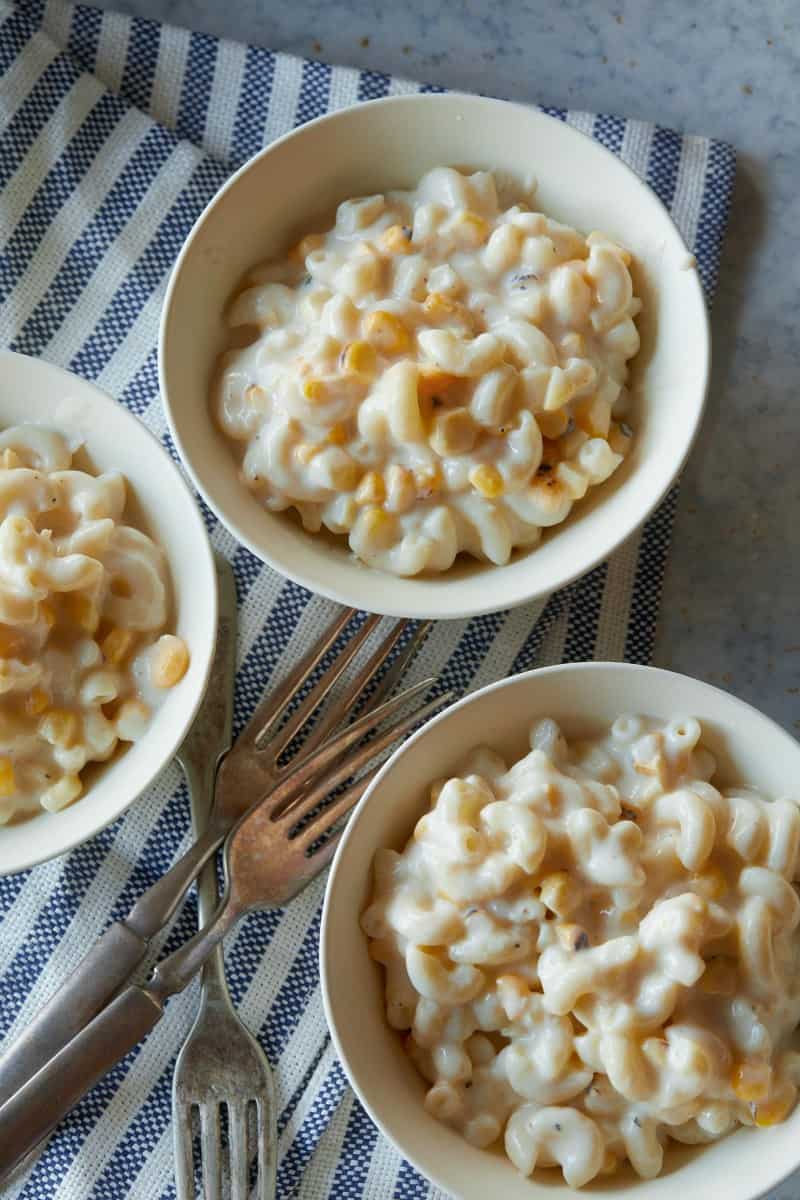 Several bowls of creamed corn mac and cheese with forks.