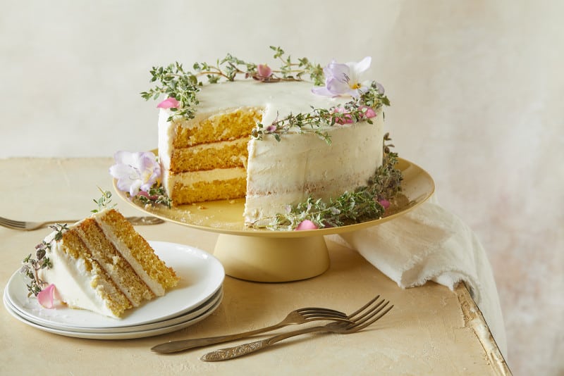 A browned butter cake with vanilla honey frosting with a slice on a plate and forks.