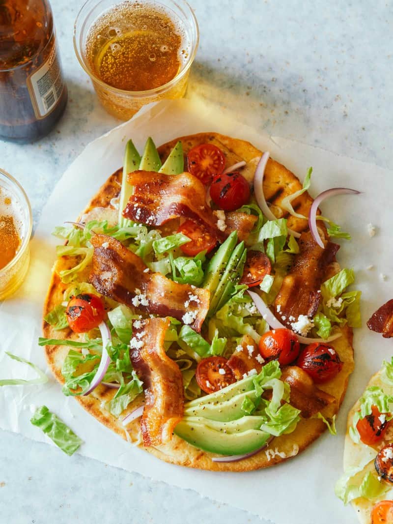 A whole grilled BLTA flatbread with drinks.