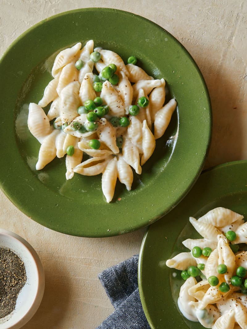 Green plates of white cheddar mac, cheese, and sweet peas.