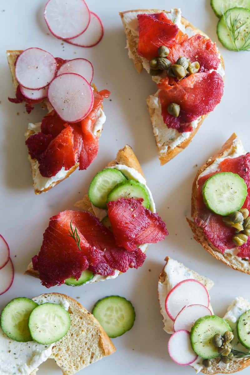 Beet cured salmon on bagel halves with cream cheese, cucumber and radish slices.