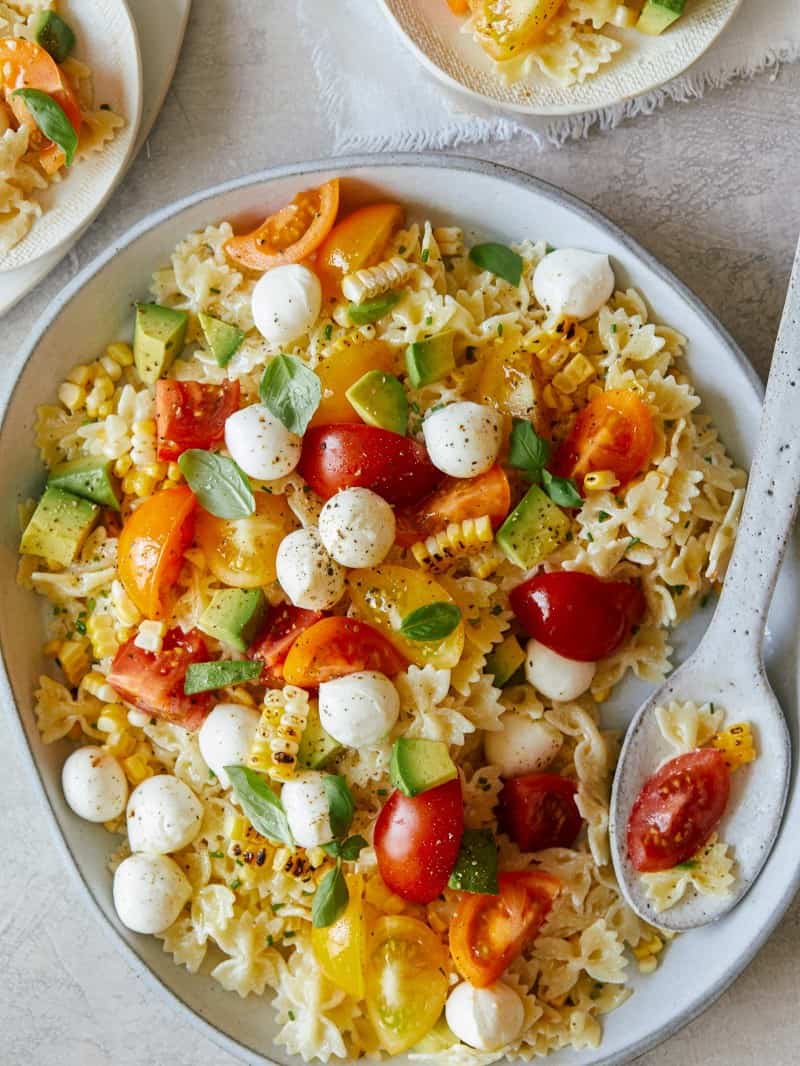 A plate of loaded pasta salad with a spoon.