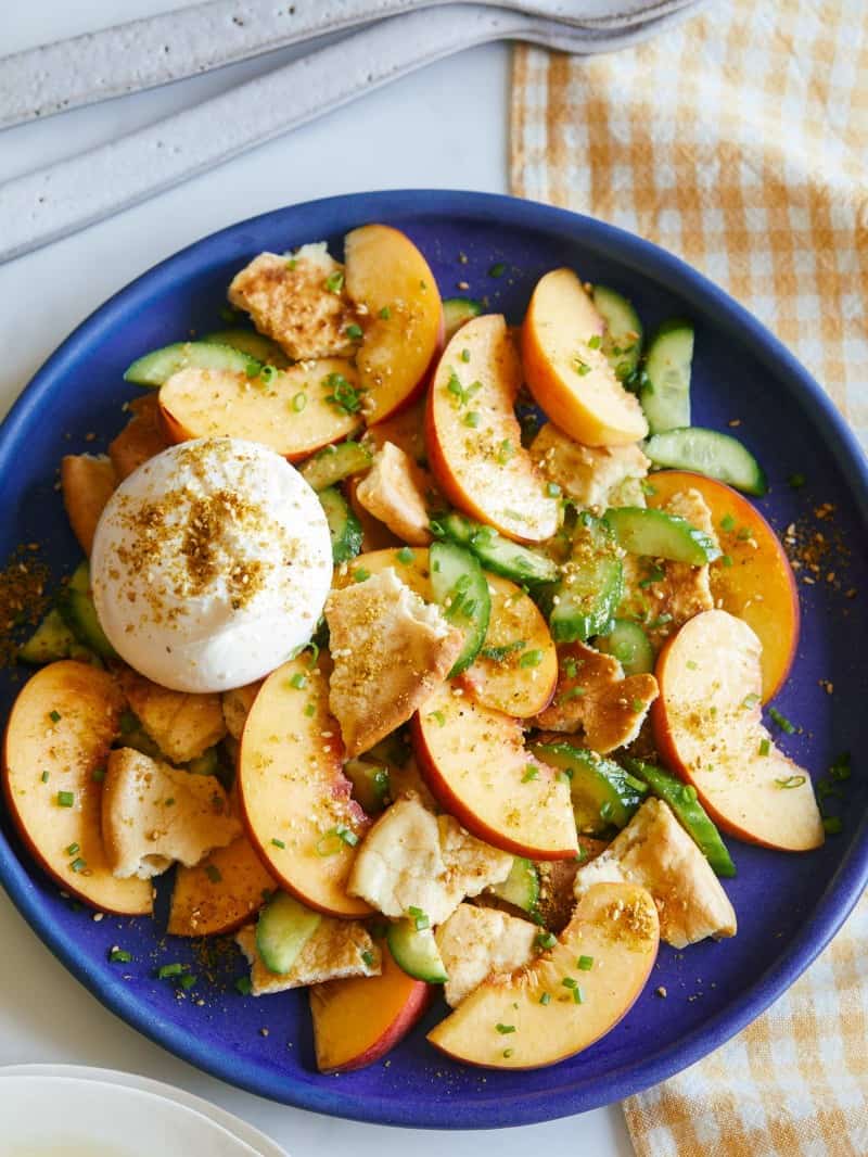 Peach panzanella salad on a blue plate.