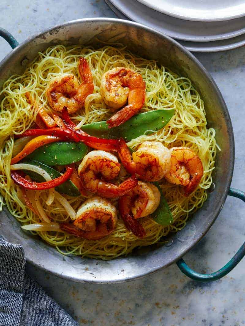A pot of singapore noodles with shrimp and peppers.