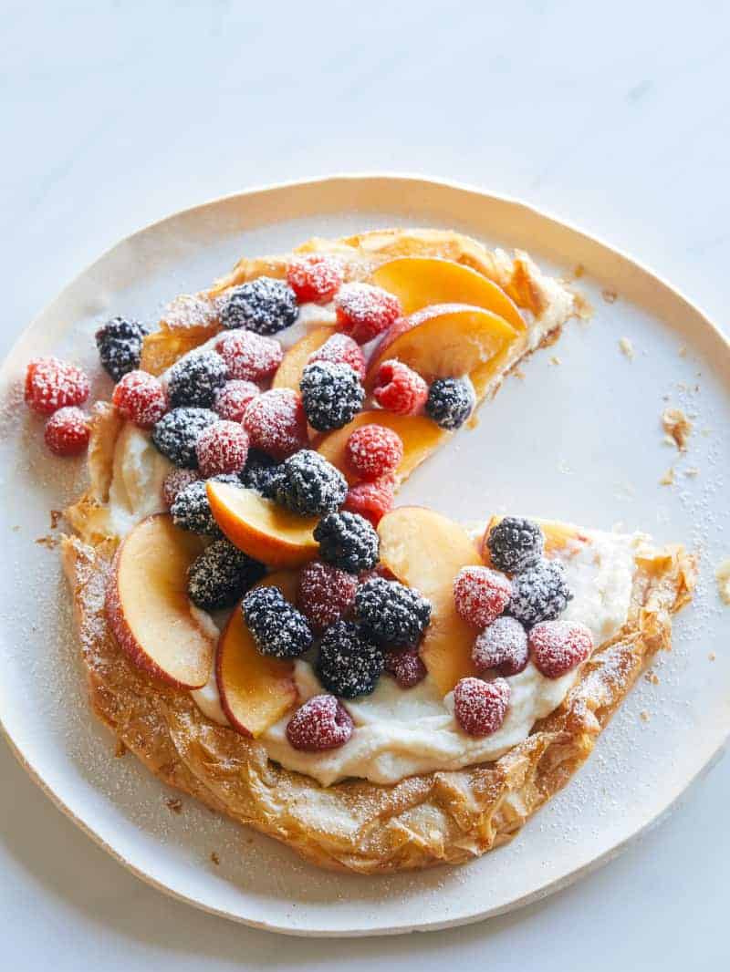 A summer fruit ricotta crostata with a slice removed.