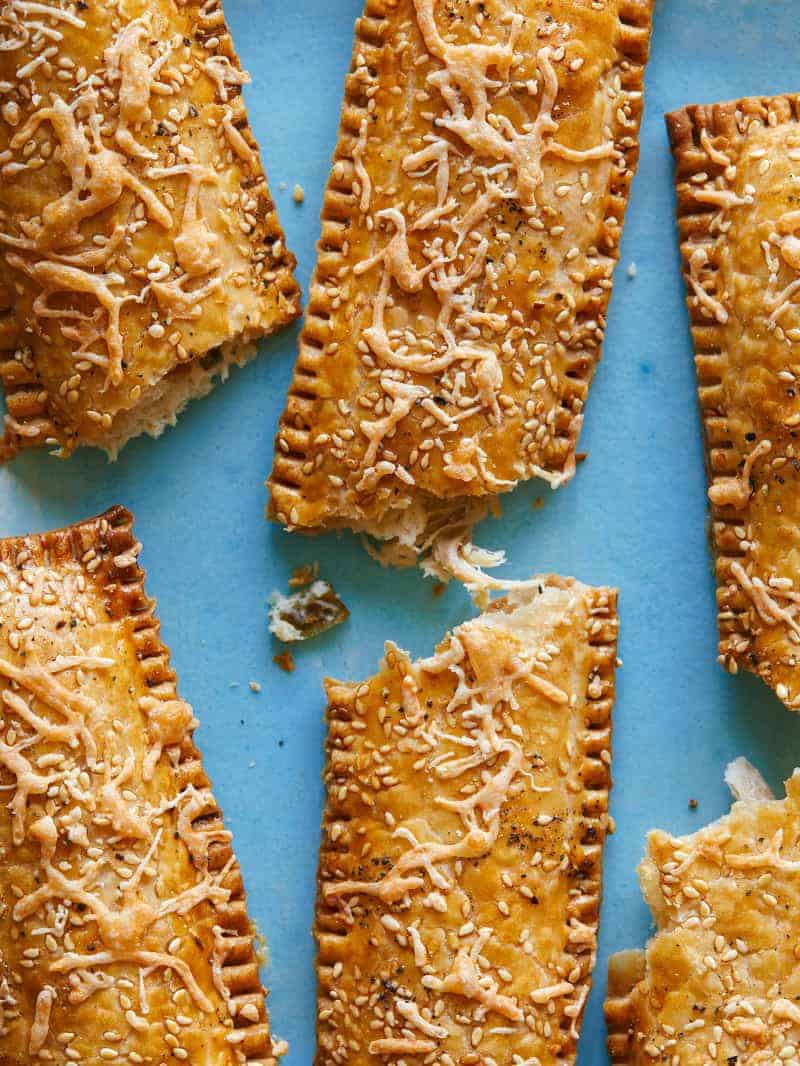 A close up of creamy chicken and green onion hand pie sticks, broken in half.