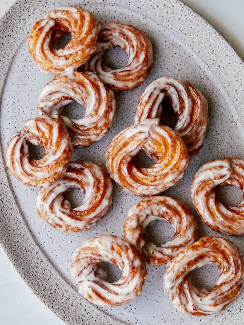 Pumpkin crullers with vanilla bean glaze on a platter.