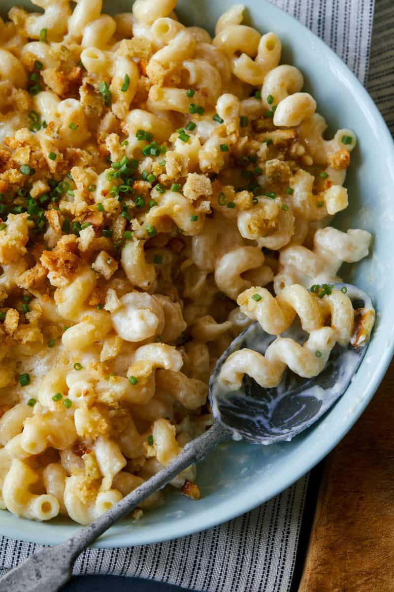 A close up of taleggio mac and cheese topped with buttery crackers with a spoon.